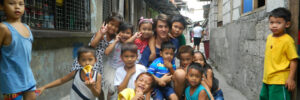 Bild: Kinder und Freiwilliger in einer engen Gasse