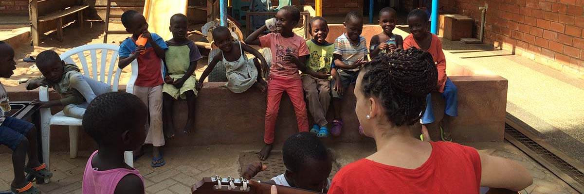 Freiwillige mit Gitarre und Kindern