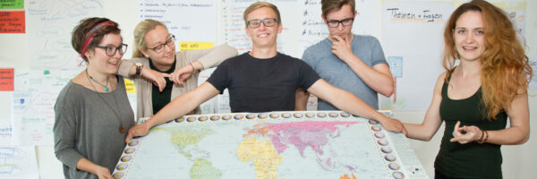 Eine Gruppe an Freiwilligen hält eine Weltkarte.