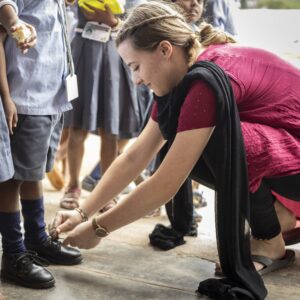 Eine junge Frau bindet einem Kind die Schuhe