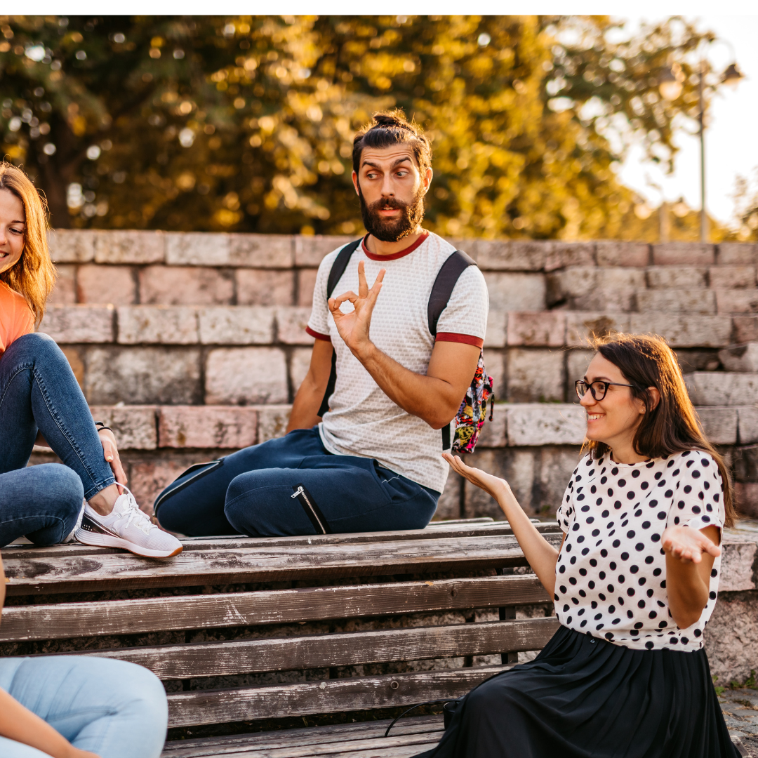 c iStock.com urbazon eine Gruppe von jungen Menschen sitzt auf einer Bank und kommuniziert in Gebärdensprache.