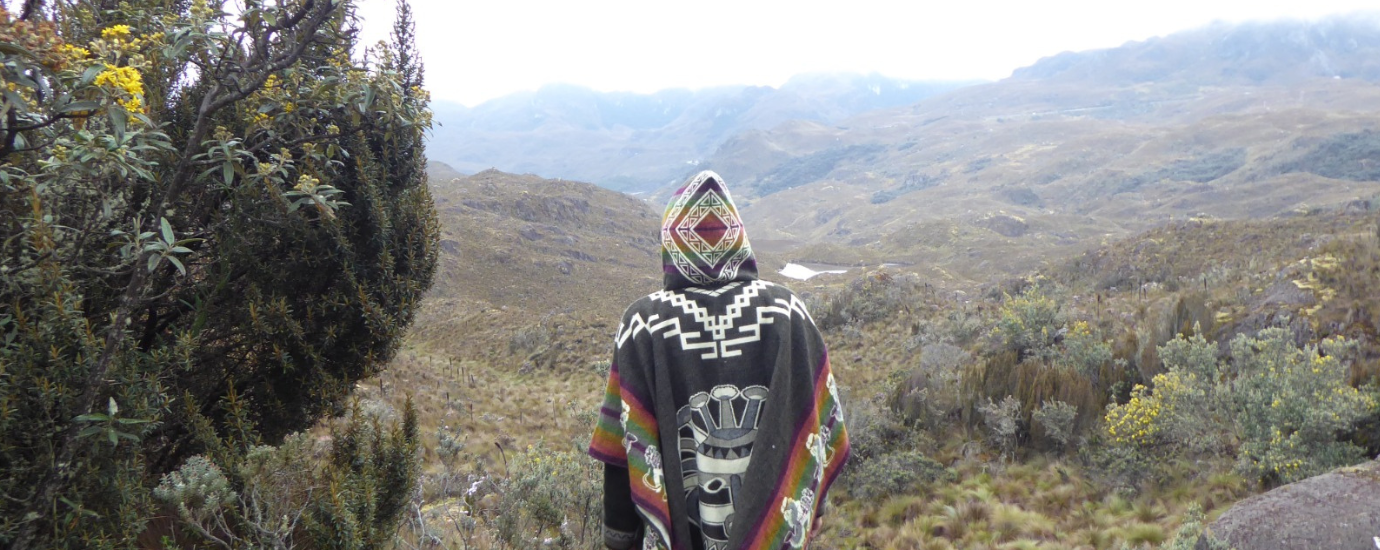 c Jakob Kempf x WeltWegWeiser Eine Person mit einem bunten Pncho geht durch eine bergige Landschaut