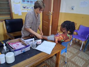 Christina am arbeiten, nimmt Blutdruckmessung bei Dame vor