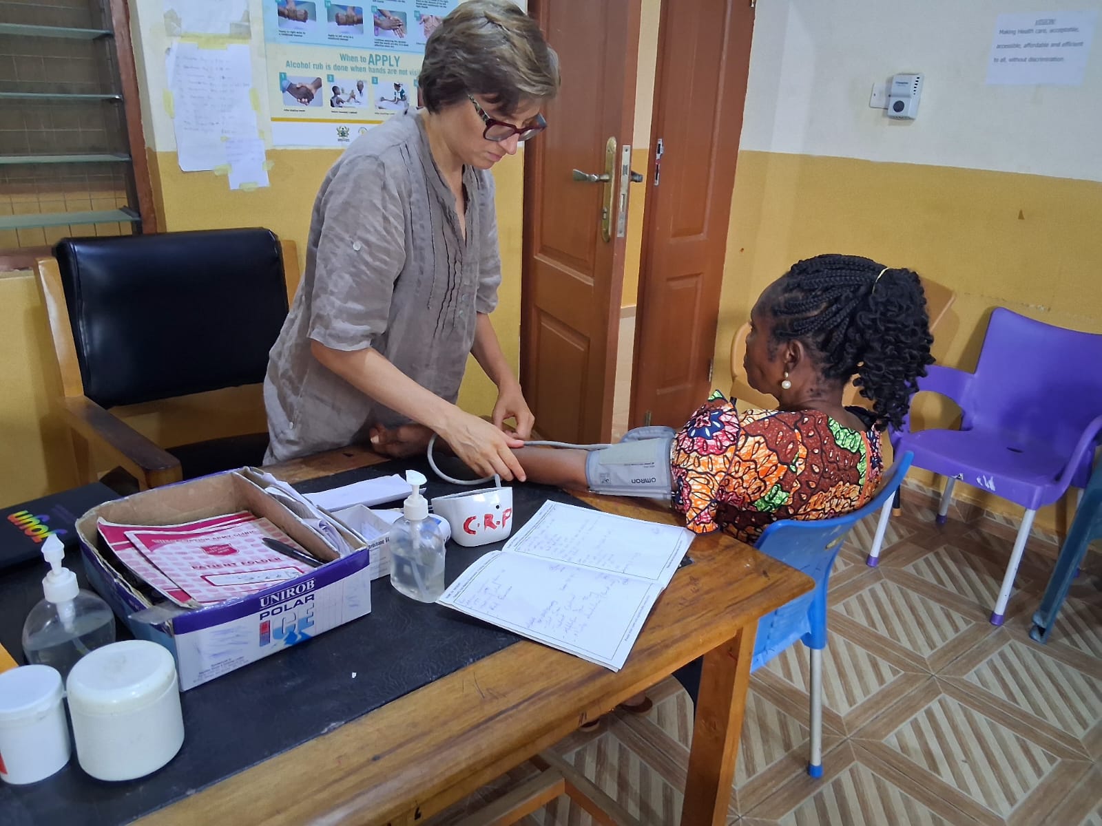 Christina am arbeiten, nimmt Blutdruckmessung bei Dame vor