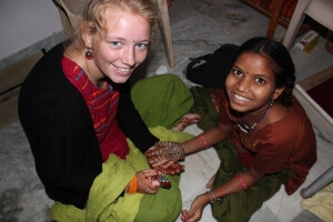 Freiwillige sitzt neben einheimischer Frau und betrachten ihre Henna-Tattoos