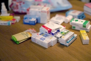 Ein paar Medikamentenschachteln liegen unsortiert auf einer Tischplatte
