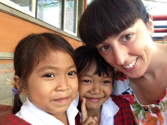 Bild: Zwei Kinder und eine Freiwillige lächeln in die Kamera