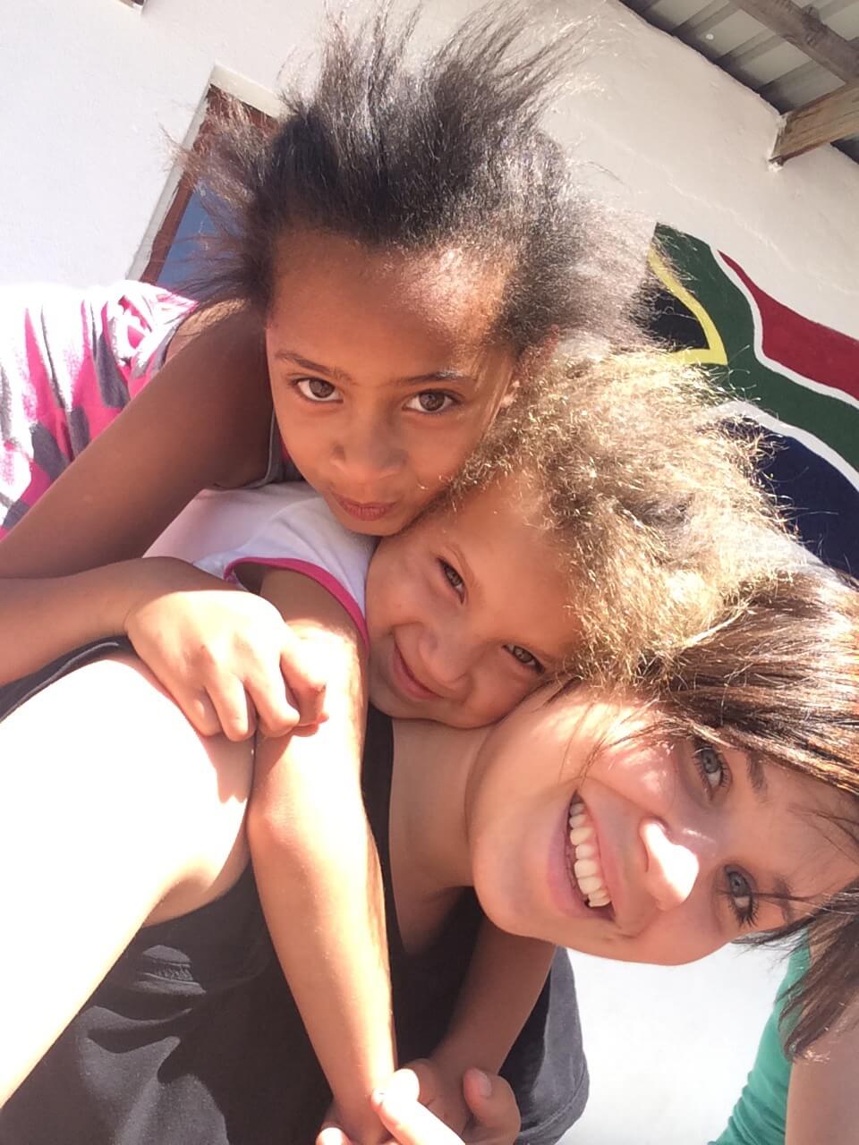 Bild: Zwei Kinder und eine Freiwillige lächeln in die Kamera