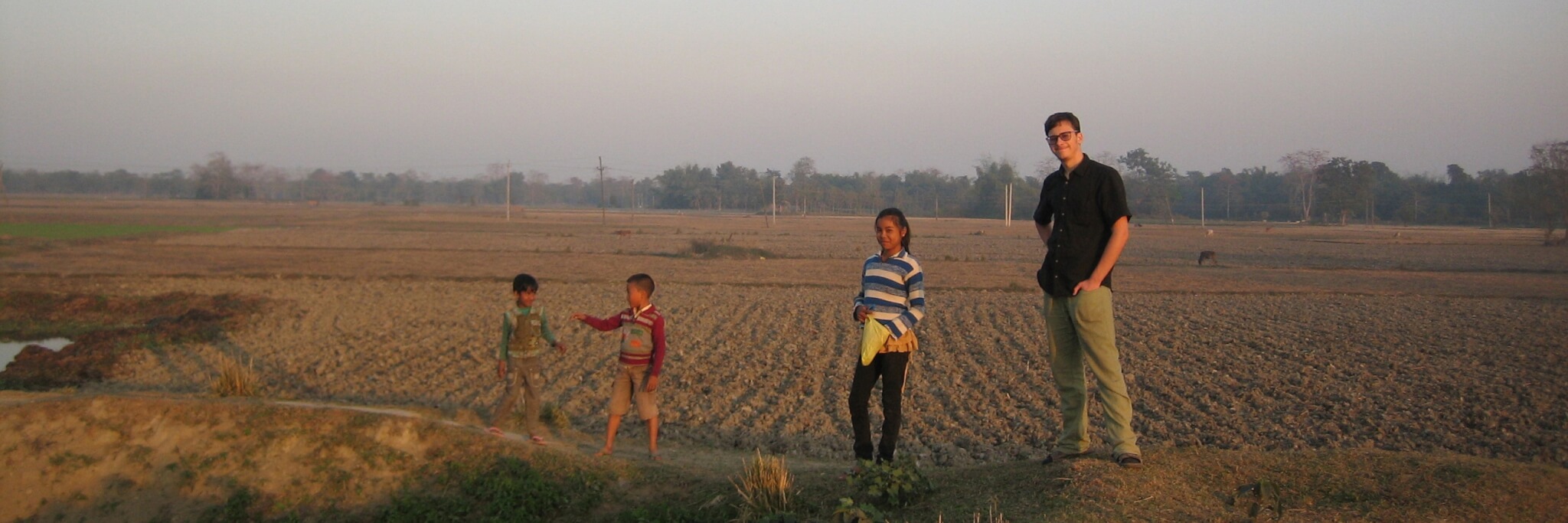 Bild: Kinder stehen mit einem Freiwilligen auf einem Feld