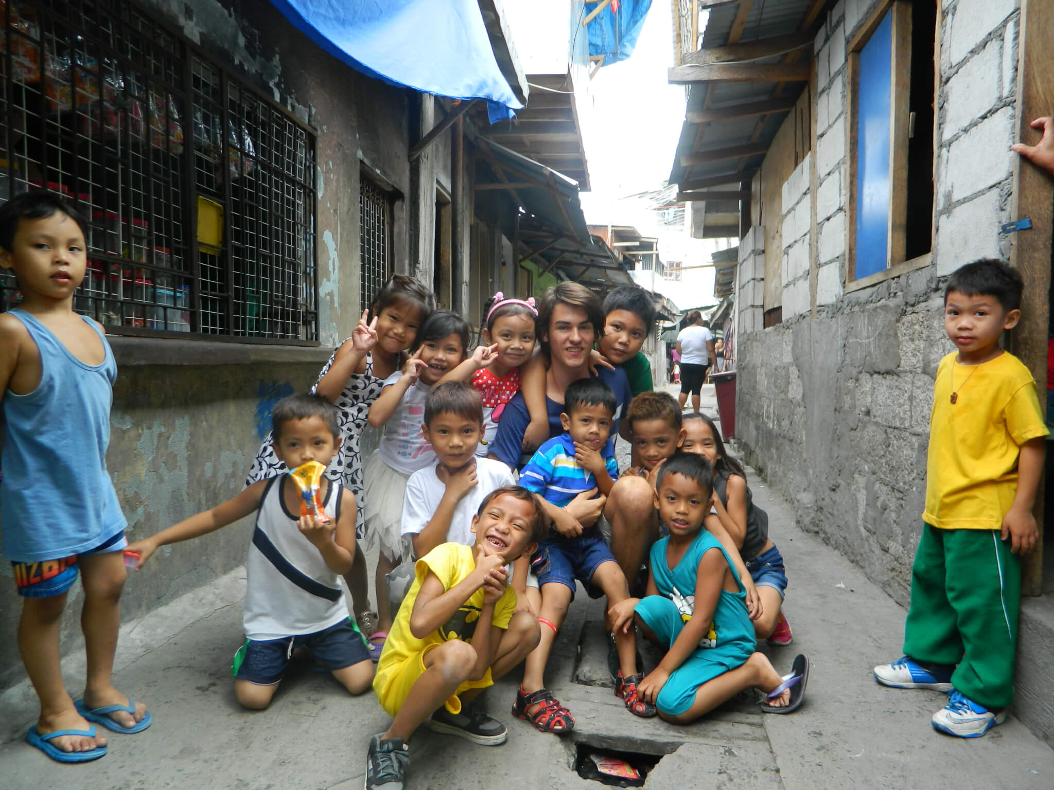 Bild: Kinder und Freiwilliger in einer engen Gasse