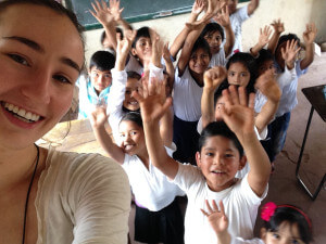 Freiwillige macht ein Selfie mit einheimischen Kindern, die ihre Arme in die Höhe strecken