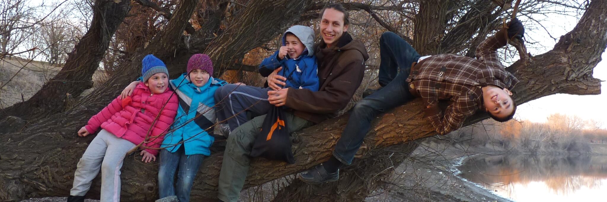 Bild: Freiwilliger sitzt mit Kindern auf einem Baum