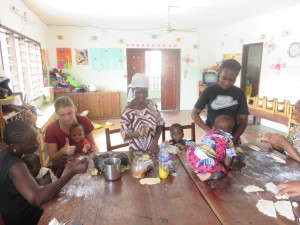 Freiwillige, Frauen und Kinder sitzen um einen Tisch und bereiten Essen zu