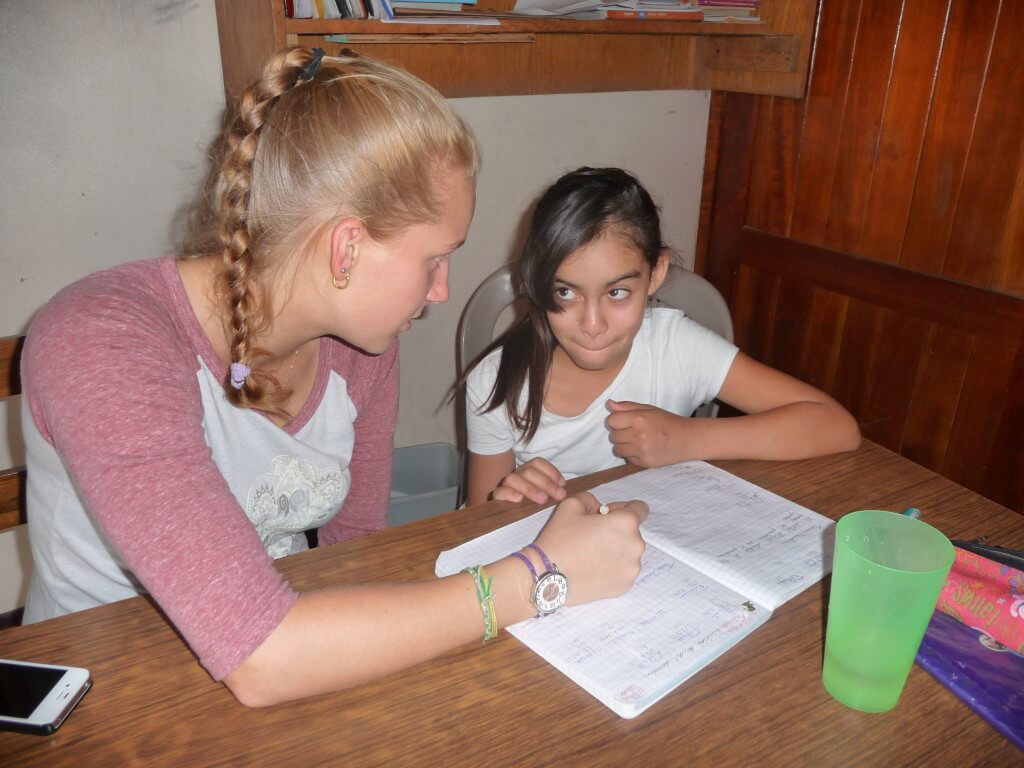 Bild: Freiwillige mit Kind bei den Hausaufgaben