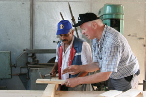 Ein einheimischer wird von einem Freiwilligen beim bearbeiten von Holz angeleitet