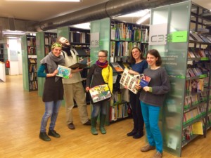 Fünf junge Frauen stehen in einer Bücherei und halten Bücher in ihren Händen