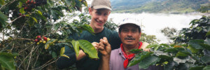 Ein Freiwilliger und ein Einheimischer stehen in einer Kaffee-Plantage