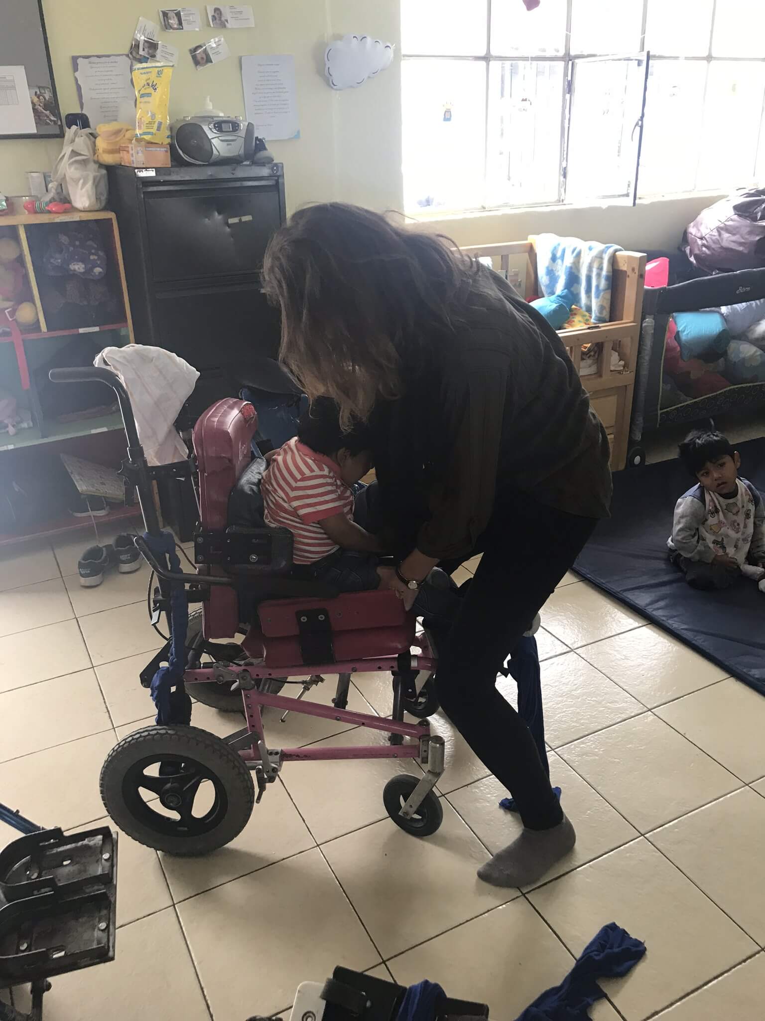Frewillige hilft Kind in Rollstuhl