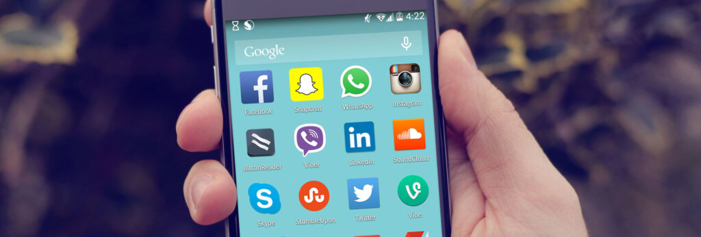 Eine Hand hält ein Handy, am Bildschirm sieht man diverse Apps