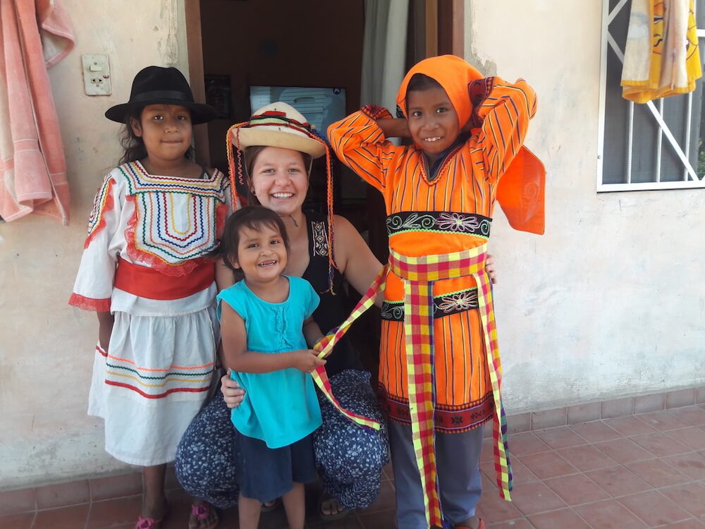 Eine Freiwillige mit drei Kindern, von denen zwei traditionelle Kleidung tragen