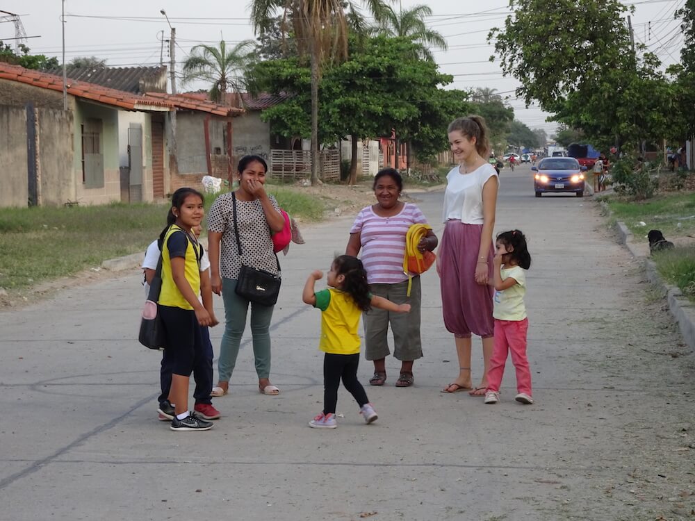 Eine weibliche Freiwillige steht mit einer Gruppe von Frauen und Kindern auf der Straße