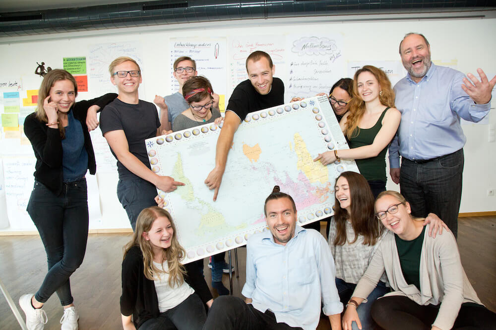 Gruppe von Freiwilligen hält eine überdimensionale Weltkarte in den Händen