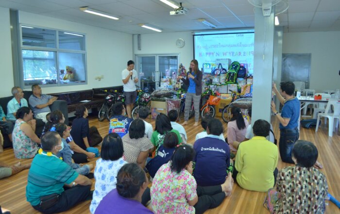Vera Hofbauer und ein Kollege halten einen Vortrag in Thailand vor einigen Menschen, die in einem Klassenzimmer am Boden sitzen